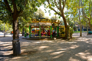 A man waits for his child at the Villa Borghese carousel in the Borghese Gardens of Rome, Italy