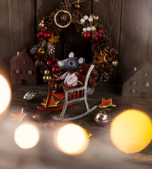 new year and christmas background. wooden toy mouse in rocker and winter wreath behind it.backgrounds for greeting cards