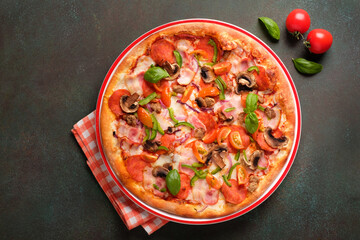 Pizza, napkin, cherry tomatoes and basil leaves on dark green background. Copy space, top view.