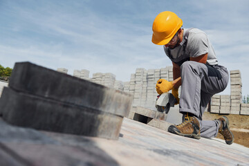 Concentrated at work. Man in yellow colored uniform have job with pavement