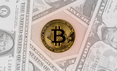 A physical version of bitcoins and dollar bills. The coin is yellow. Conceptual image of a worldwide cryptocurrency and digital payment system.