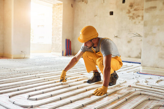 Worker in yellow colored uniform installing underfloor heating system