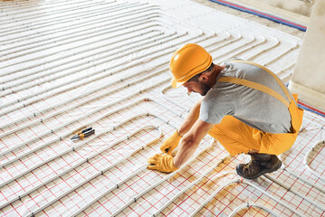 Worker in yellow colored uniform installing underfloor heating system