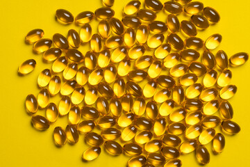 omega 3 vitamins or fish oil scattered on a yellow background.