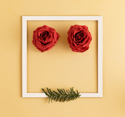 Red rose with white frame and Christmas tree branch on pastel yellow background. Flat lay, top view, copy space