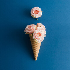Rose flowers and ice cream cone on blue background. Minimal concept. Flat lay.