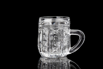 Empty crystal mug on a black background with reflection. Crystal kitchen utensils.