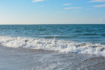 Waves on sand beach with blue sky