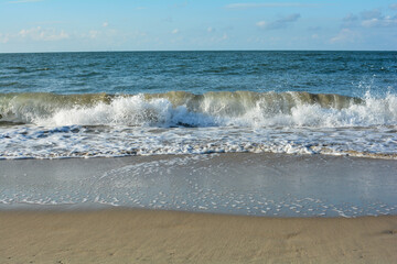 Waves on sand beach with blue sky
