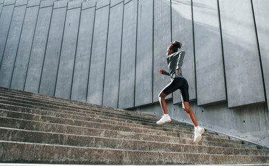 Young african american woman in sportive clothes have workout outdoors at daytime