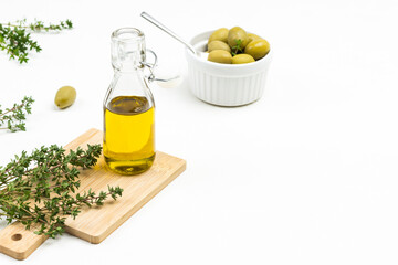 Olive oil bottle and thyme sprigs on board. Olives in ceramic bowl