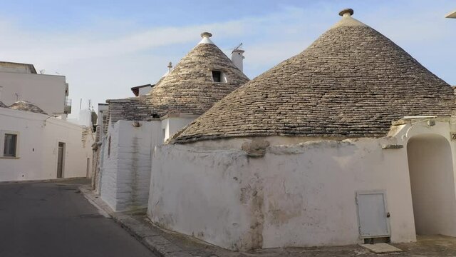 Alberobello, Italy. Aerial view of unique trullo buildings within narrow streets. Lovely traditional houses with white facades and cone-shaped rooftops. High quality 4k footage