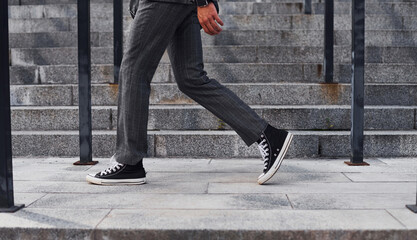 Close up view. Young successful businessman in grey formal wear is outdoors in the city