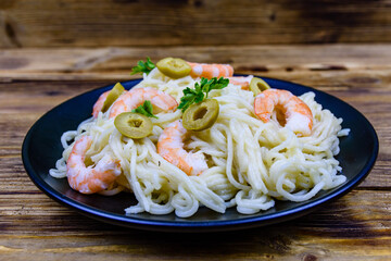 Italian pasta with shrimps and olives in a black plate