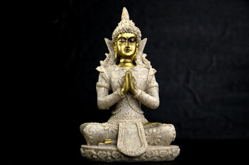 Fototapeta premium Golden Gautama Buddha with Dark Rocks Isolated on Black