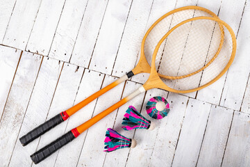 Badminton shuttlecocks and wooden paddles. Accessories for amateur games on a wooden table.