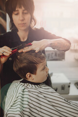 Fototapeta premium The work of the barbershop. Haircut of a boy in a barbershop. Children's haircut