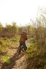 A boy rides a balance bike in a clearing. Spring mood. Sun