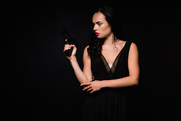 Fototapeta premium brunette woman in dress holding gun isolated on black