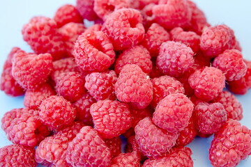 Raspberry pattern, blue background, top view.Pattern of ripe red raspberry on blue background. Vegan food, detox concept
