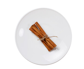 cinnamon sticks tied with rustic rope on a white saucer, isolated on white.
