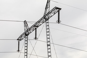 High voltage pole detail isolated on cloudy sky.
