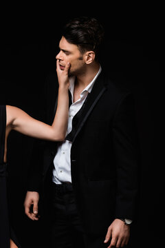 woman touching face of man in suit isolated on black