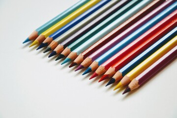 Colorful wooden crayons on the piece of white paper. Set of colored wooden pencils close-up. White background