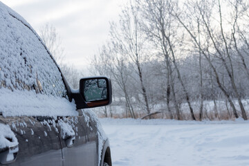 Snow covered vehicle with rear view mirror in landscape