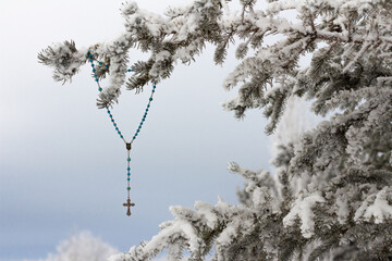 Rosary hanging in snowy evergreen tree