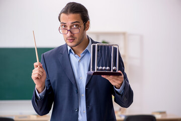Young male teacher physicist in front of green board