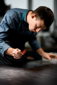 male holds spoon with granules and sprinkles them on the table surface