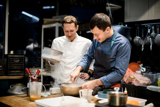 two smiling male chefs are cooking in the kitchen