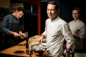 smiling male chef with frying pan in his hand looks at the camera
