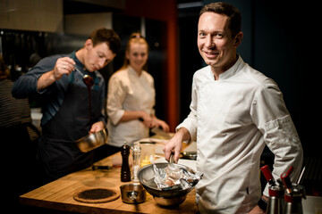 smiling man with frying pan in his hand looks at the camera