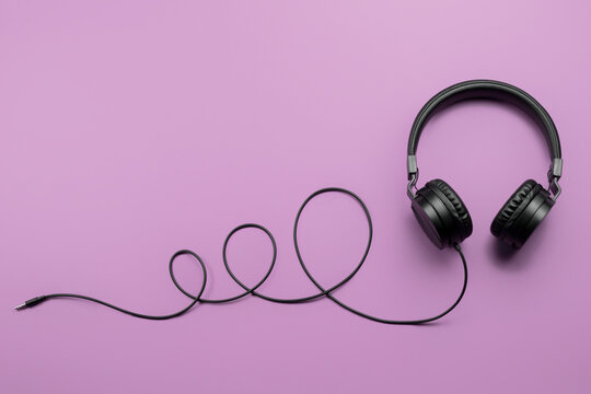 Stylish modern black headphones on purple background.
