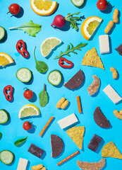 Healthy and junk food diet choices concept made from snacks in pattern on blue background.