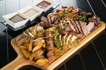 Pork kebab. Barbecue tasty meat ot the black plate. Potato, meat, and sausages.