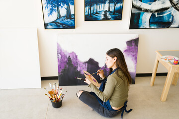 Young woman using a palette to mix different paints for her canvas