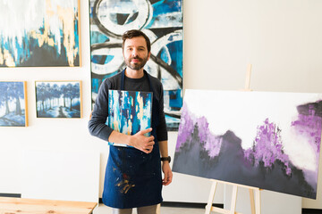 Male painter showing his new pieces of art at the gallery