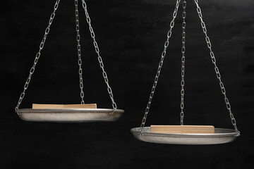 Balance scales on black background with wooden stands. Balance concept. Copy space.