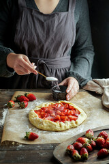 Galette with fresh strawberry process of preparation, young woman hands, working with dough