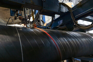 Automatic machine is welding to  spiral welded pipe. The welding system welds the pipe, first along...