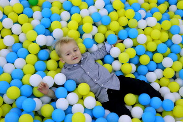 Fototapeta na wymiar A blond boy in a gray shirt plays in a children's entertainment center selective focus.