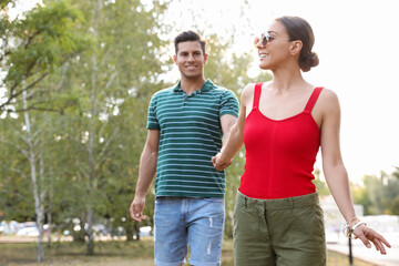 Lovely couple walking together in park on sunny day