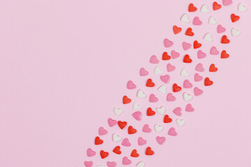 Heart shaped candies scattered on pink background