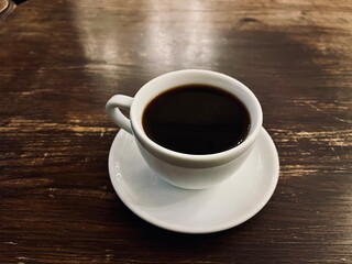black coffee in a white cup on a wooden table