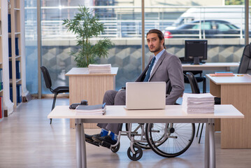 Young male employee in wheel-chair working in the office
