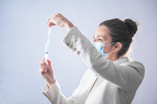 M&eacute;dico mujer, preparando la vacuna para la cura del COVID 19, SARS-CoV-2, cura definitiva, vacuna en tonos azules y colores neutros, mujer preparando la inyecci&oacute;n  en una jeringa para curar el SARS-Co