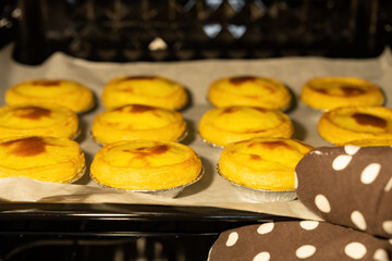 taking out fresh made egg tarts from an oven